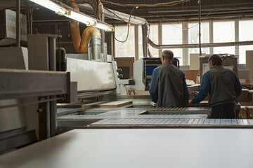 Two friendly colleagues standing close to machine