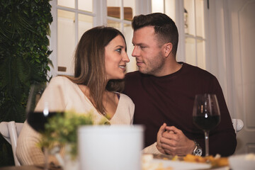 Beautiful young adult couple passionately look at each other while waiting for restaurant food.Valentine's Day