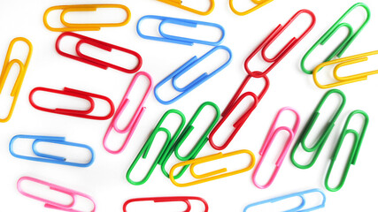 A lot of multicolored paper clips isolated on a white background. Close-up on stationery
