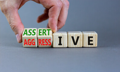 Aggressive or assertive symbol. Businessman turns wooden cubes, changes the word Aggressive to...
