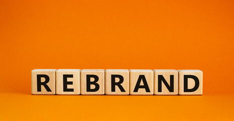 Rebrand and brand symbol. The concept word Rebrand on wooden cubes. Beautiful orange table, orange background, copy space. Business rebrand and brand concept.