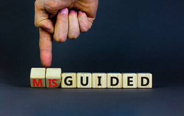 Guided or misguided symbol. Businessman turns wooden cubes and changes the word misguided to guided. Beautiful grey table, grey background, copy space. Business and guided or misguided concept.