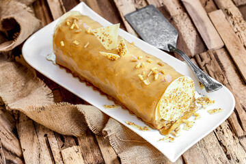 Bûche au chocolat blanc, noisette, pomme et caramel sur table en bois