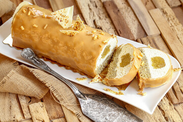 Bûche au chocolat blanc, noisette, pomme et caramel sur table en bois