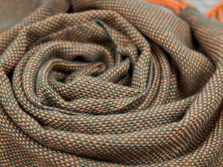 The interwoven of green and orange threads of the handmade fabric. Draped woolen shawl or plaidy, close up