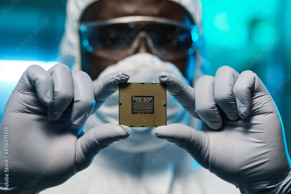 Poster Gloved hands of African man in protective coveralls showing you microchip while holding it in front of camera