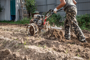 plows the land with a cultivator, preparing it for planting vegetables