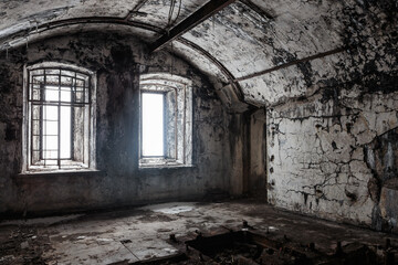 casemate of an abandoned fort, illuminated by daylight through a pair of barred windows
