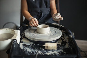 Girl hands working with clay on a Potter's wheel close up. Tradi