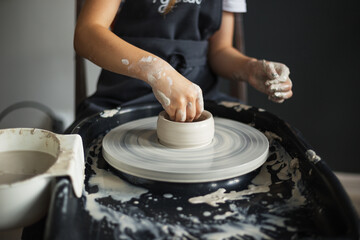Hands of girl creating bowl on potter's wheel. Traditional craft
