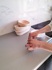 A woman kneads dough on the kitchen table for baking bread