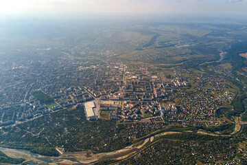 Aerial view from airplane window at high altitude of earth covered with white thin layer of misty haze and distant clouds at sunset