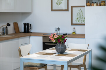 Image of beautiful flowers in vase on the kitchen table in empty domestic kitchen