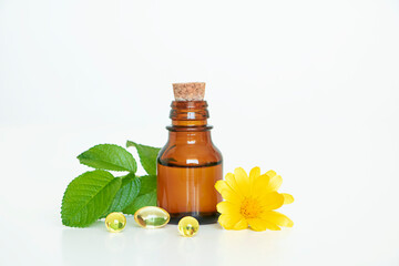 Concept alternative medicine. Close up medical dark bottles and yellow capsules of vitamins and yellow  calendula flower on white background. Copy space