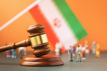 Judge gavel, flag and plastic toy men on colored background, Iran lawsuit concept