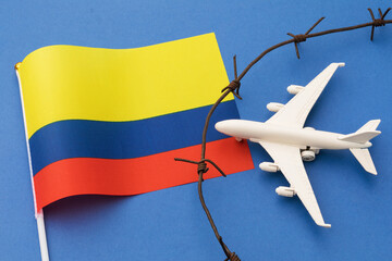 Toy plane, Colombian flag and barbed wire on colored background, Colombia air border violation concept