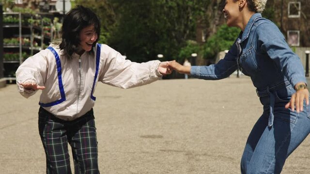 Laughing same sex couble skateboarding in the street