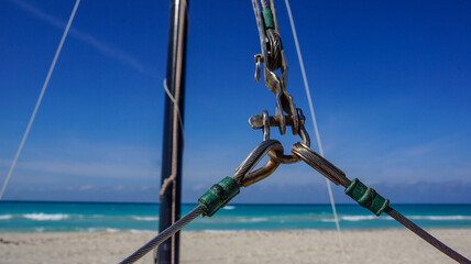 Cuba, February 2012. Sheets are fastened on a yacht on a white sand beach against the backdrop of...