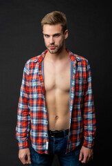 Fototapeta na wymiar Serious handsome guy with fit torso hairless chest posing in open plaid shirt, depilation