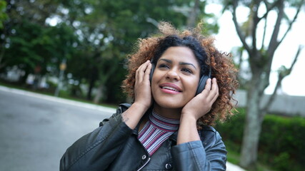 Naklejka premium Woman listening to good news podcast wearing headphone outside in street