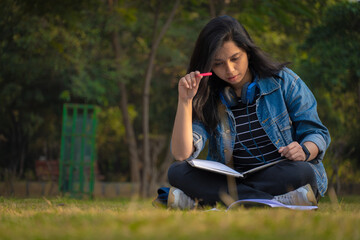 Obraz premium Indian student at college campus full size image reading books and watching camera