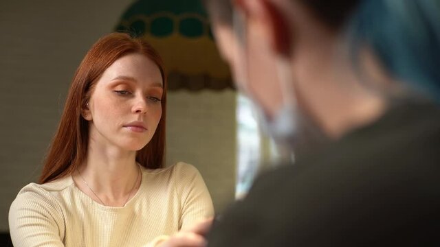 Close-up view from back of unrecognizable female master in protective mask and gloves polishing cuticle cut point on nails with electric manicure machine, with special polishing replaceable nozzle.