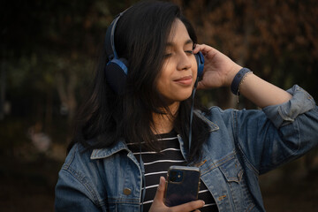 Beautiful girl listening music using her phone and headphones