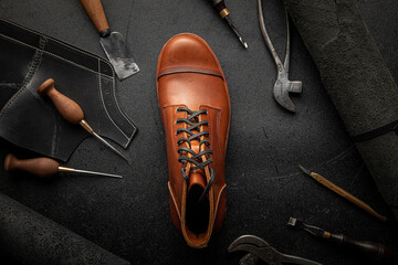 Handcrafted brown leather shoe with cobbler tools on the backgound