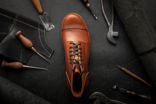 Handcrafted brown leather shoe with cobbler tools on the backgound