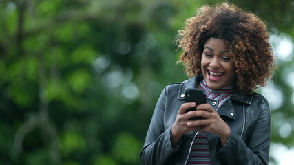 Excited black woman celebrating good news on phone notification. Person receives positive message