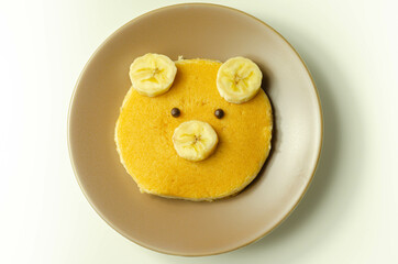 Creative meal for a child, pancake with banana and chocolate  in a face little bear  shape