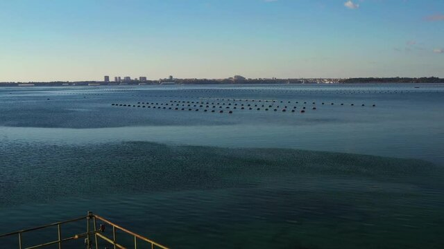 Mussel farming in the Mar Piccolo with Taranto in the background and boat survey for mussel harvesting
