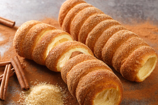 Trdelnik or trdlo is a traditional sweet cake made of yeast dough, which is held around a stick and then fried and sprinkled with sugar and cinnamon close up on the table. Horizontal