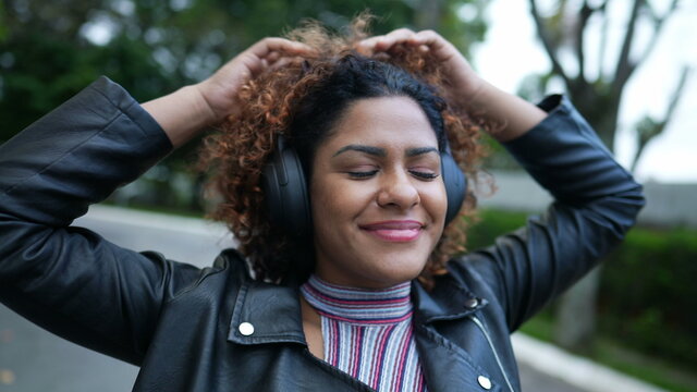 Carefree Black Woman Dancing To Music Outside In Street Wearing Headphones