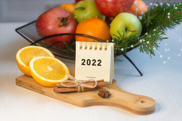 Fruit tea, various fruits in a basket on the table. Calendar 2022, winter mood and spruce branches.