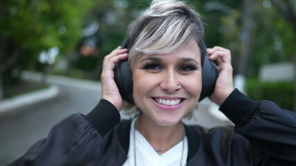 Happy young woman putting headphones and listening to song. person dancing to music