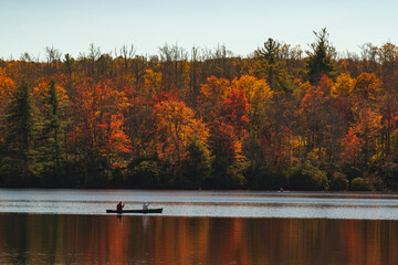 People kayaking in lake by autumn forest