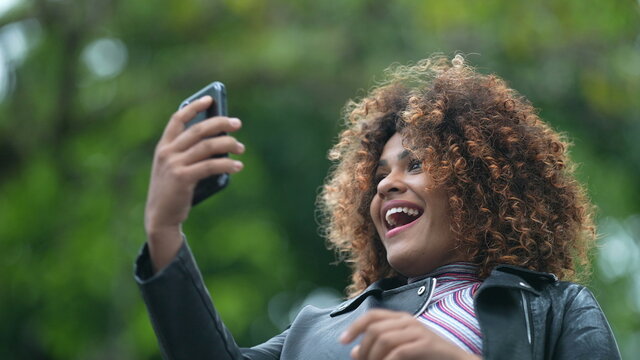 Happy Black Woman Surprised By Good News On Cellphone Standing Outside Smiling