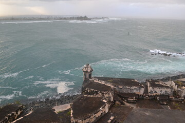 Stormy ocean and cloudy sky with old fortification wall, view from Castillo San Felipe del Morro, Old San Juan Puerto Rico - obrazy, fototapety, plakaty