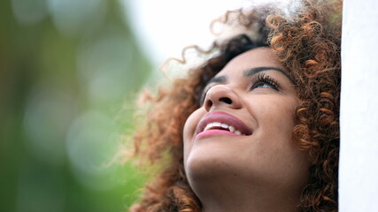 Black hispanic woman closing eyes in contemplation. African Brazilian girl opening eye to sky