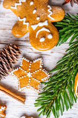 Christmas gingerbread and sweets are placed on wooden desk. Cookies and sweet food in shape of stars and snow flakes. Winter theme, rustic style. Pine trees on the side. Candy stick and other spice.