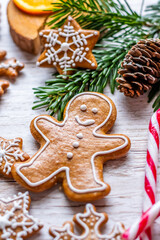 Christmas gingerbread and sweets are placed on wooden desk. Cookies and sweet food in shape of stars and snow flakes. Winter theme, rustic style. Pine trees on the side. Candy stick and other spice.
