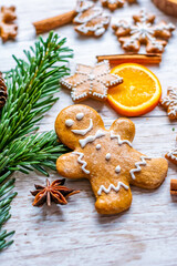 Christmas gingerbread and sweets are placed on wooden desk. Cookies and sweet food in shape of stars and snow flakes. Winter theme, rustic style. Pine trees on the side. Candy stick and other spice.