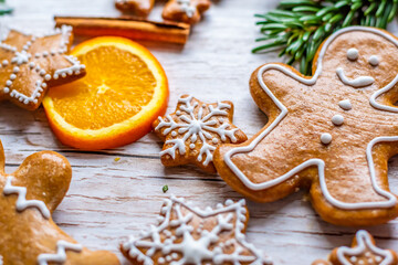 Christmas gingerbread and sweets are placed on wooden desk. Cookies and sweet food in shape of stars and snow flakes. Winter theme, rustic style. Pine trees on the side. Candy stick and other spice.