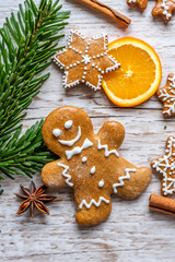 Christmas gingerbread and sweets are placed on wooden desk. Cookies and sweet food in shape of stars and snow flakes. Winter theme, rustic style. Pine trees on the side. Candy stick and other spice.