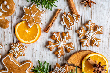 Christmas gingerbread and sweets are placed on wooden desk. Cookies and sweet food in shape of stars and snow flakes. Winter theme, rustic style. Pine trees on the side. Candy stick and other spice.