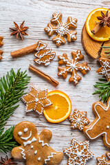 Christmas gingerbread and sweets are placed on wooden desk. Cookies and sweet food in shape of stars and snow flakes. Winter theme, rustic style. Pine trees on the side. Candy stick and other spice.