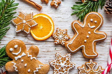 Christmas gingerbread and sweets are placed on wooden desk. Cookies and sweet food in shape of stars and snow flakes. Winter theme, rustic style. Pine trees on the side. Candy stick and other spice.