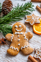 Christmas gingerbread and sweets are placed on wooden desk. Cookies and sweet food in shape of stars and snow flakes. Winter theme, rustic style. Pine trees on the side. Candy stick and other spice.