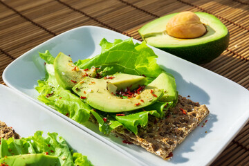 Healthy avocado toasts for breakfast, sliced avocado, lettuce leaves and spices. Whole food concept.